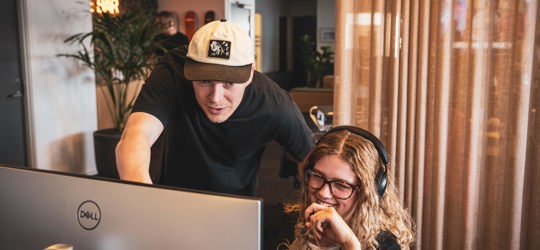 En ung mand og en ung kvinde arbejder sammen ved computere i et moderne lokale