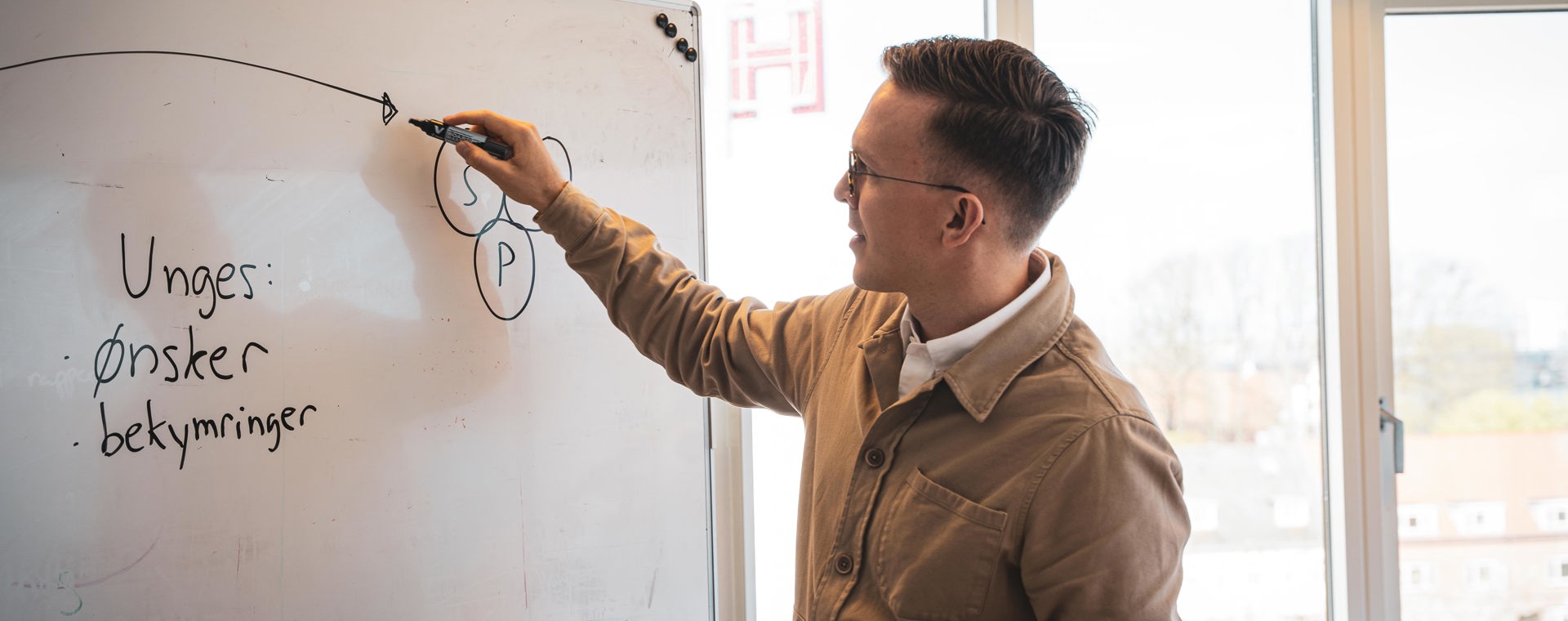 Underviser ved whiteboard tegner diagram med tusser i undervisningslokale