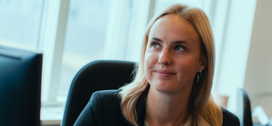 Camilla Amorsen smiler og kigger opad i et kontorlokale