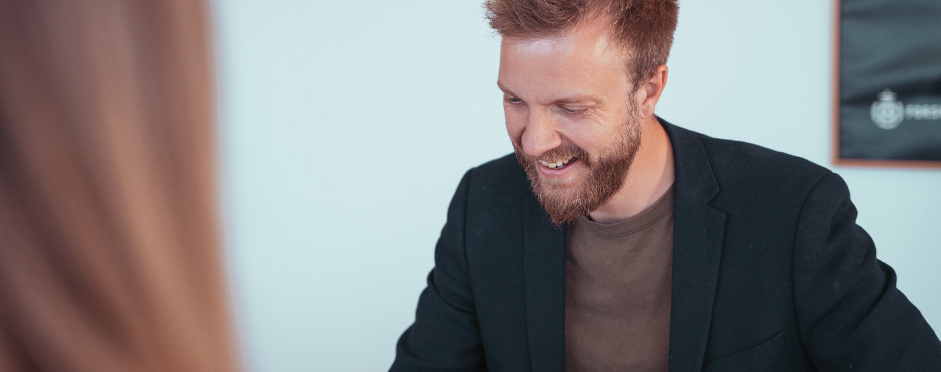 Smilende mand i blazer i samtale med en person uden for billedet
