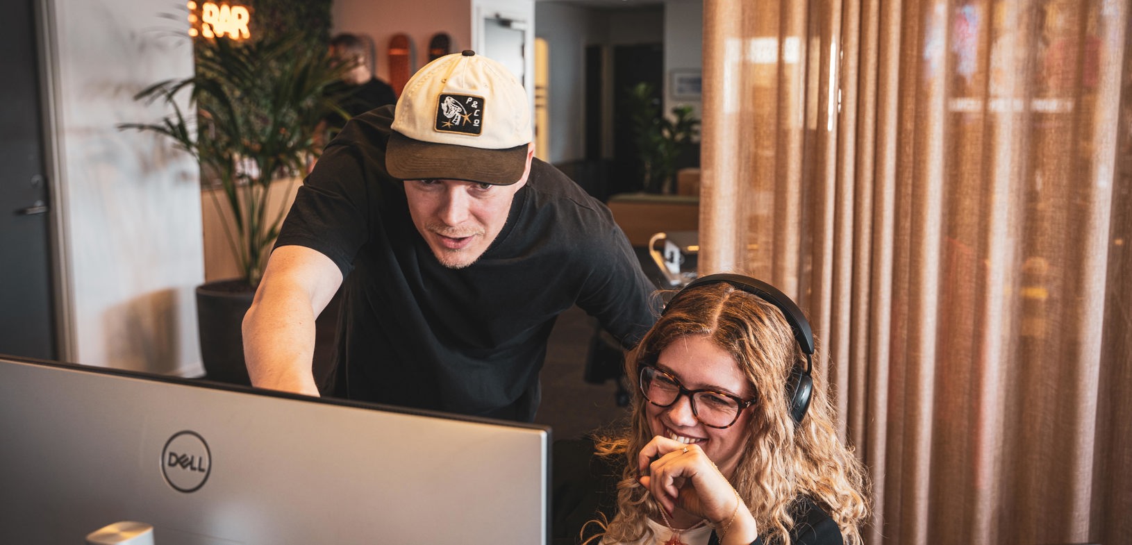 To personer arbejder sammen foran en computer i et moderne lokale med varmt lys