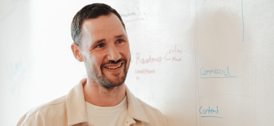 Smilende lærer foran whiteboard med skrevne begreber